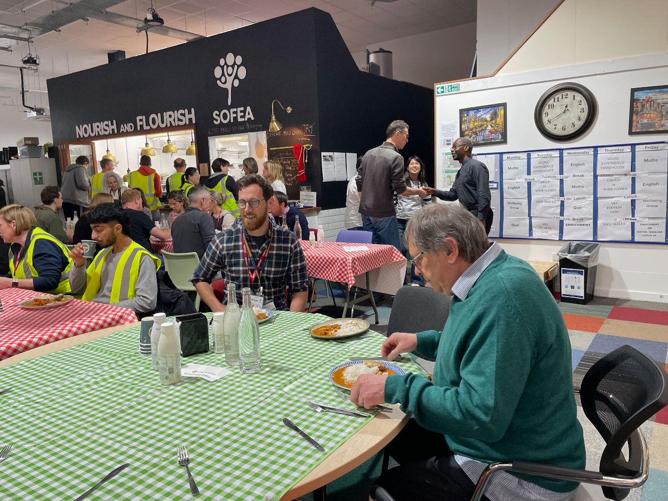 IDRM Deputy Building and Facilities Manager enjoys sitting down to a meal at one of SOFEA's community larders with a SOFEA volunteer.