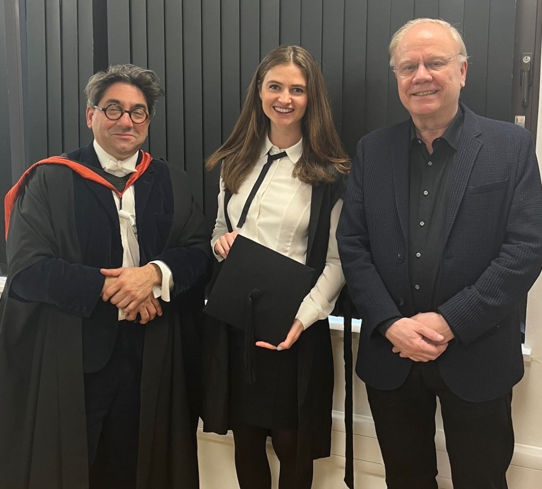 Three people stand shoulder to shoulder facing the camera. 