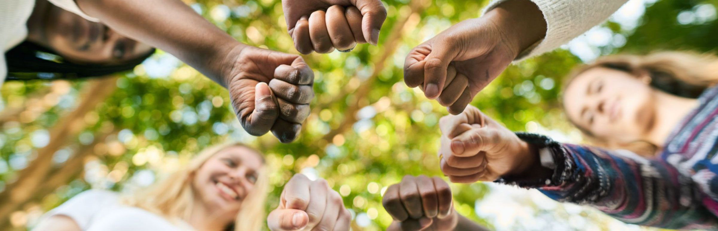 Mixed diverse group of circle people placing hands onto the centre