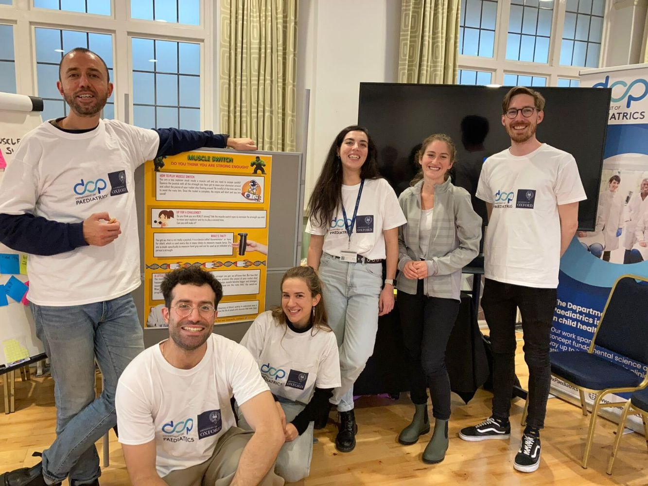 Researchers sitting and standing in front of posters at festival stall
