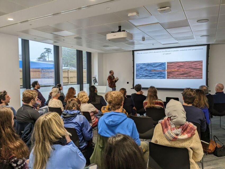 An audience of students listens to a speaker in a seminar room
